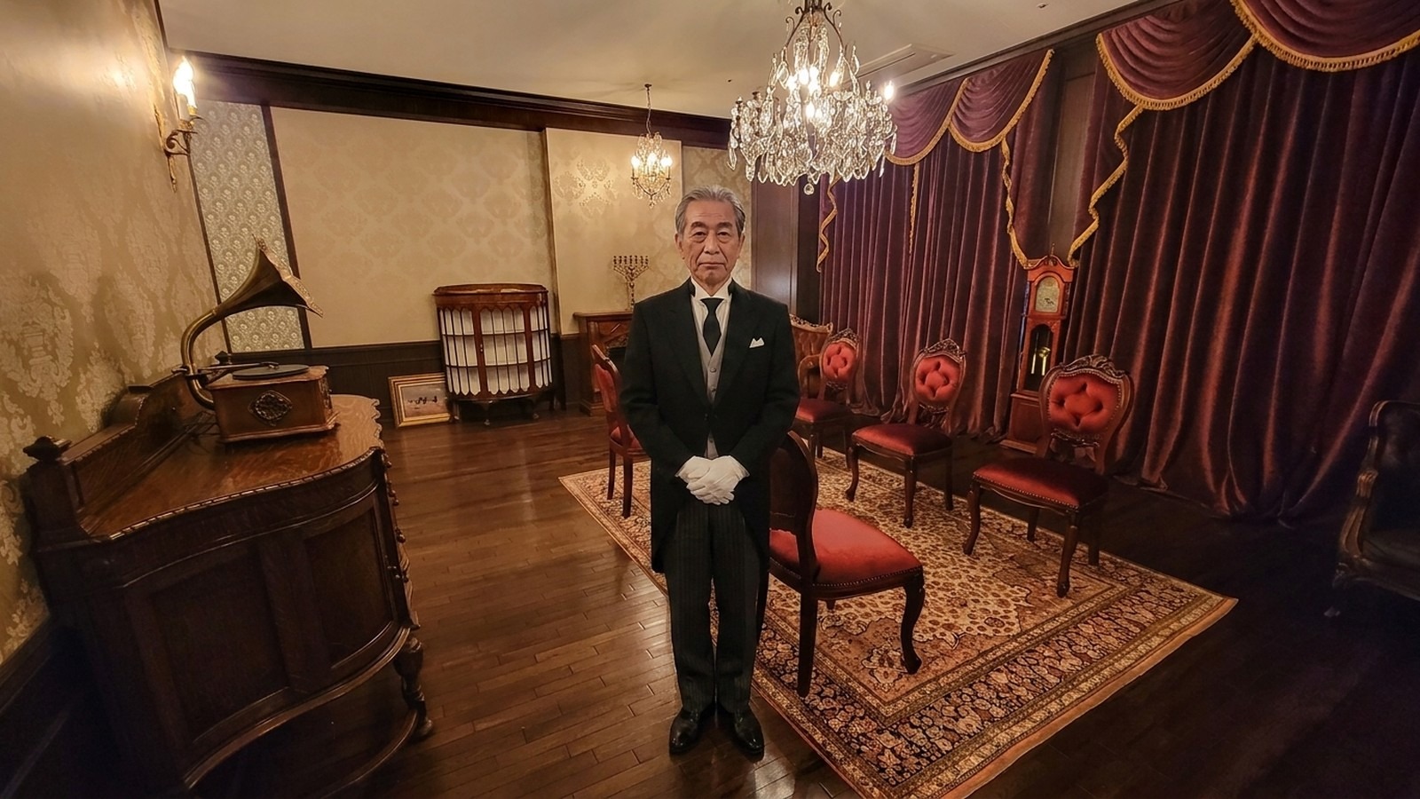 重厚な扉と装飾を備えた応接室で執事が佇む格式ある室内の様子