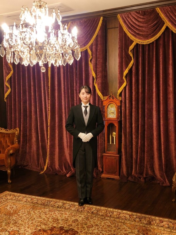 白手袋と教科書を手にした日本執事アカデミーの正装の女性執事