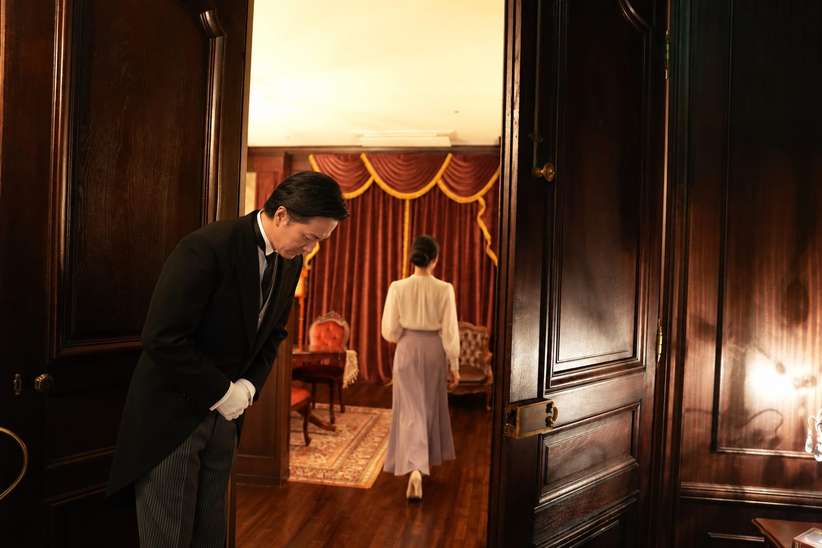 A butler seeing a guest off outside the door (photograph of the house)