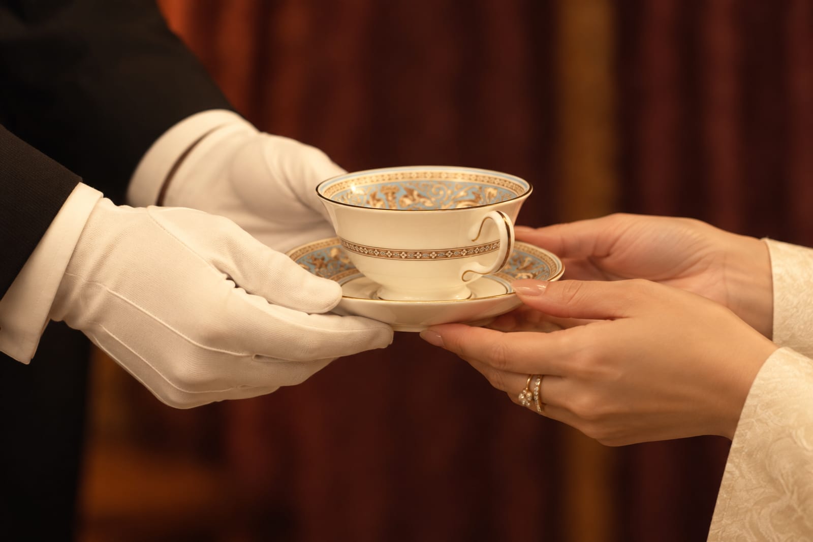 Hands of a butler offering a cup of tea (Queen\'s Butler photograph)